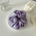 Detalle de un coletero plisado lavanda sobre un posavasos de piedra blanca elegante - Morado