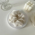 Gros plan du chouchou plissé blanc sur un support en pierre au style minimaliste - Beige