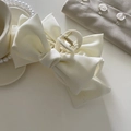 Detalle de la pinza para el pelo con lazo de satén blanco y textura de tela elegante - Blanco