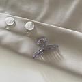 Detalle de pinza para pelo gris mármol sobre fondo de tela beige con botones - Gris