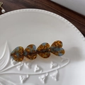 Detalle del clip de pelo de corazón ámbar con textura de carey y base de metal dorado - Azul Café