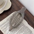 Primer plano de una pinza para el pelo de acrílico gris translúcido en papel vintage - Gris