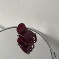 Detailed view of a glossy burgundy resin small hair claw clip reflected on a mirror - Burgundy