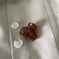 Macro detail of glossy amber brown mini hair claw clip on beige fabric texture - Red Brown Fan
