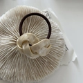 Detailed macro view of cream marble resin twist knot decoration on a brown elastic hair tie - Braided Style