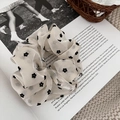 Détail du chouchou en dentelle de résille blanc cassé avec motif floral noir sur un livre - Fleur