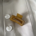 Pince à cheveux ambre avec texture marbrée posée sur un blazer beige élégant - Vert Jaune Rectangle