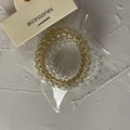 Close-up of amber gold and clear spiral telephone cord hair ties on branded card - Beige