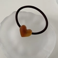 Detail of amber acetate heart pendant on a black elastic hair tie for women - Brown