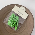 Dettaglio di 5 fermagli per capelli verde acceso in confezione minimalista su piatto in ceramica - Verde
