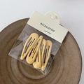 Dettaglio di cinque fermagli per capelli gialli e beige su un piatto con confezione card - Giallo