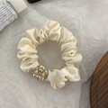 Dettaglio dell'elastico per capelli in raso crema con perla floreale dorata e cristallo - Elastico per capelli