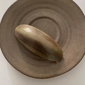 Détail d'une barrette à cheveux marbrée marron avec finition brillante sur un plat en céramique - Café au Lait