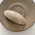 Dettaglio del fermaglio ovale color crema con finitura in resina lucida su piatto ceramico - Color Tè al Latte