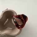 Close-up of translucent amber resin shark hair claw clip on a minimalist texture base - Tortoiseshell