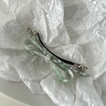 Detailed macro view of green marbled acetate bow hair clip on a white textured background - White Green