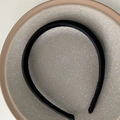 Détail d'un serre-tête en satin noir posé sur une assiette en céramique grise élégante - Noir