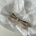 Macro view of cream white acetate bow hair clip with mother-of-pearl marble texture - Shell White