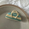 Detail view of large marble texture hair claw clip in blue and cream on ceramic plate - Blue