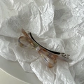 Detail of acetate bow hair clip showing marble texture and silver metal spring fastener - AB Color
