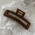 Vue détaillée d'une pince à cheveux rectangulaire évidée marron ambre au fini brillant - Marron