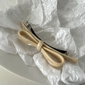 Detail of elegant beige acetate bow hair clip with polished finish and metal spring clip - Apricot