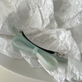 Macro shot of mint green acetate bow hair clip with polished finish on white textured paper - Mint Green