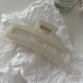 Détail d'une pince à cheveux rectangulaire crème sur fond esthétique avec accessoires - Blanc