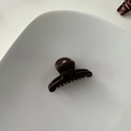 Detail of dark brown glossy hair claw with metal spring in a white ceramic dish - Hanger Shape / Dark Coffee