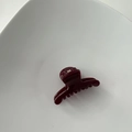 Close-up of a glossy dark red mini hair claw clip on a white ceramic tray plate - Hanger Shape / Burgundy