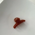 Detail view of mini amber translucent hair claw clip with golden metal spring on white background - Hanger Shape / Amber