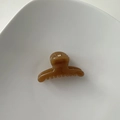 Close-up of amber brown mini hair claw clip with golden metal spring on white plate - Hanger Shape / Light Coffee