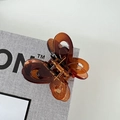 Macro view of brown butterfly hair claw clip with semi-transparent resin and metal spring - Caramel color