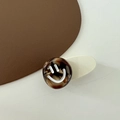 Dettaglio ravvicinato della clip per capelli marrone marmorizzata con motivo smiley bianco - Faccina Sorridente Bianca