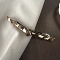 Macro detail of tortoiseshell acetate hair clip with marble texture and silver metal spring - Brown