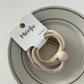 Detailed view of four Morandi colored hair bands on branded card in a ceramic dish - Round Bead Beige