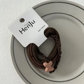 Detailansicht brauner elastischer Haarbänder auf einem Keramikteller für das Styling - Schleife Braun
