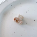 Macro detail of marble pattern acetate hair claw with a metallic gold logo finish - White Coffee