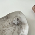Close-up of a mini silver metal flower hair claw clip with a brushed texture on a marble plate - Silver Flower