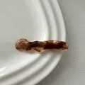Detail of wave-shaped amber acetate hair clip on a minimalist white ceramic plate - Duckbill Hair Clips / Brown