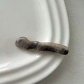 Detail of wavy resin hair clip featuring grey and black marble ink texture on a ceramic dish - Duckbill Hair Clips / Gray