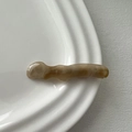 Detail of wavy amber marble resin hair clip placed on white ceramic plate - Duckbill Hair Clips / Champagne