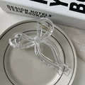 Detail of a transparent ribbon bow hair claw clip showing the inner spring and sleek design - Clear