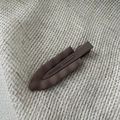 Macro shot of a dark brown matte wavy alligator hair clip on a textured fabric background - Khaki