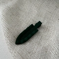 Detailed close-up of dark green matte wavy hair clip on white textured fabric background - Dark Green