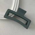 Macro view of a large matte dark gray square hair claw clip for thick hair styling - Light Blue