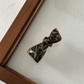 Detailed close-up of a tortoiseshell acetate bow hair clip with marble texture - Mixed Coffee