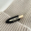 Détail d'une barrette à cheveux noire avec base en métal doré et lettrage du logo - Noir