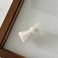 Macro detail of a creamy white acetate bow hair clip with pearlescent finish texture - Mermaid Color