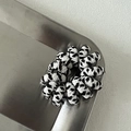 Detailopname van de zwart-witte pluche haarelastiek met een flexibele spiraalvormige basis - Broken Wit